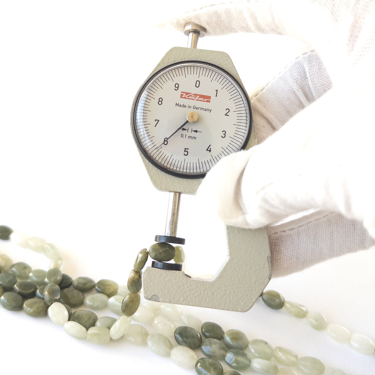 A dial gauge measures the Cat’s Eye smooth oval 6–8.5mm gemstone.
