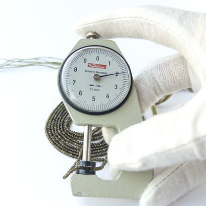A dial gauge measures the Cat's Eye faceted rondelle 2mm gemstone.