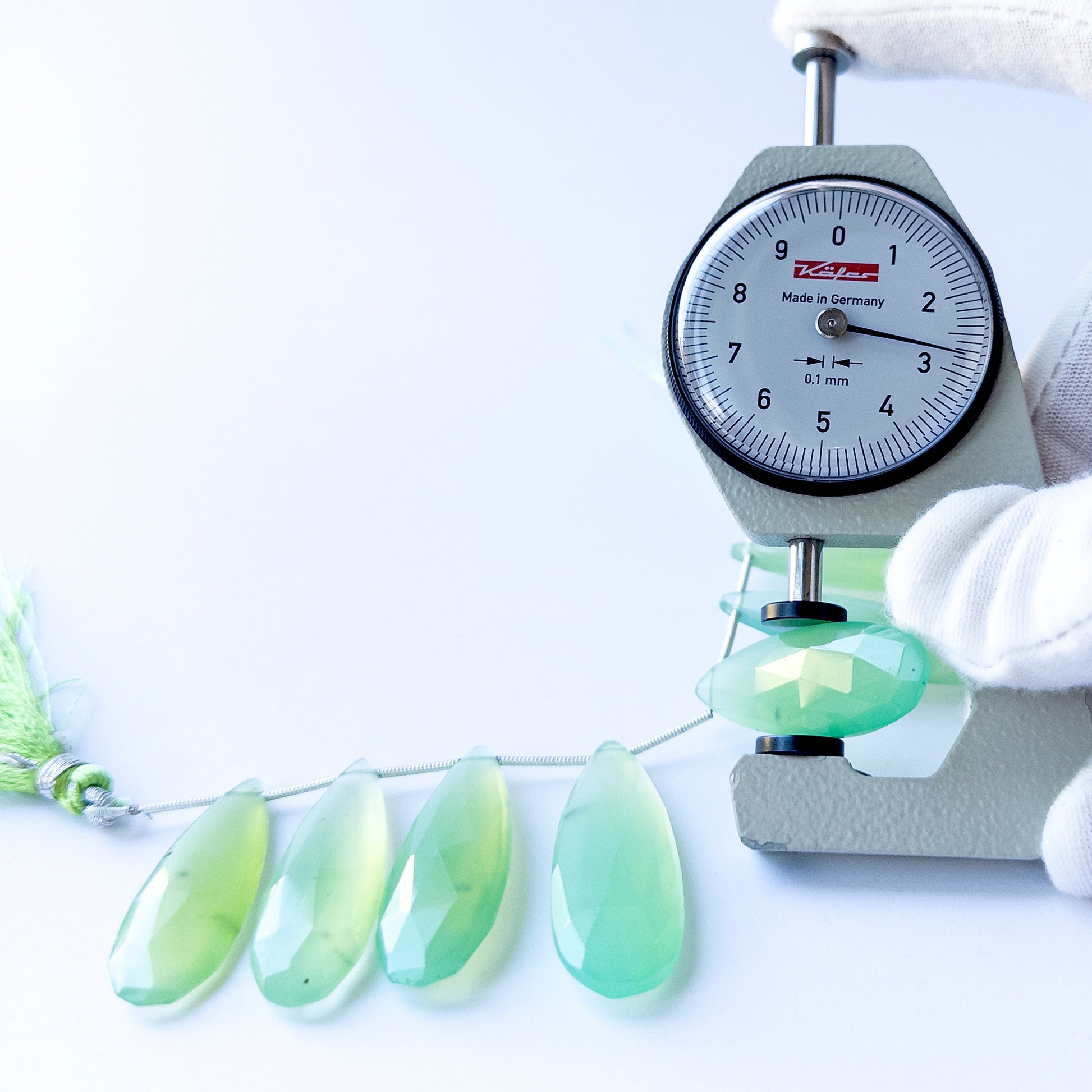 A dial gauge measures the Chalcedony faceted briolette 28–39mm gemstone.