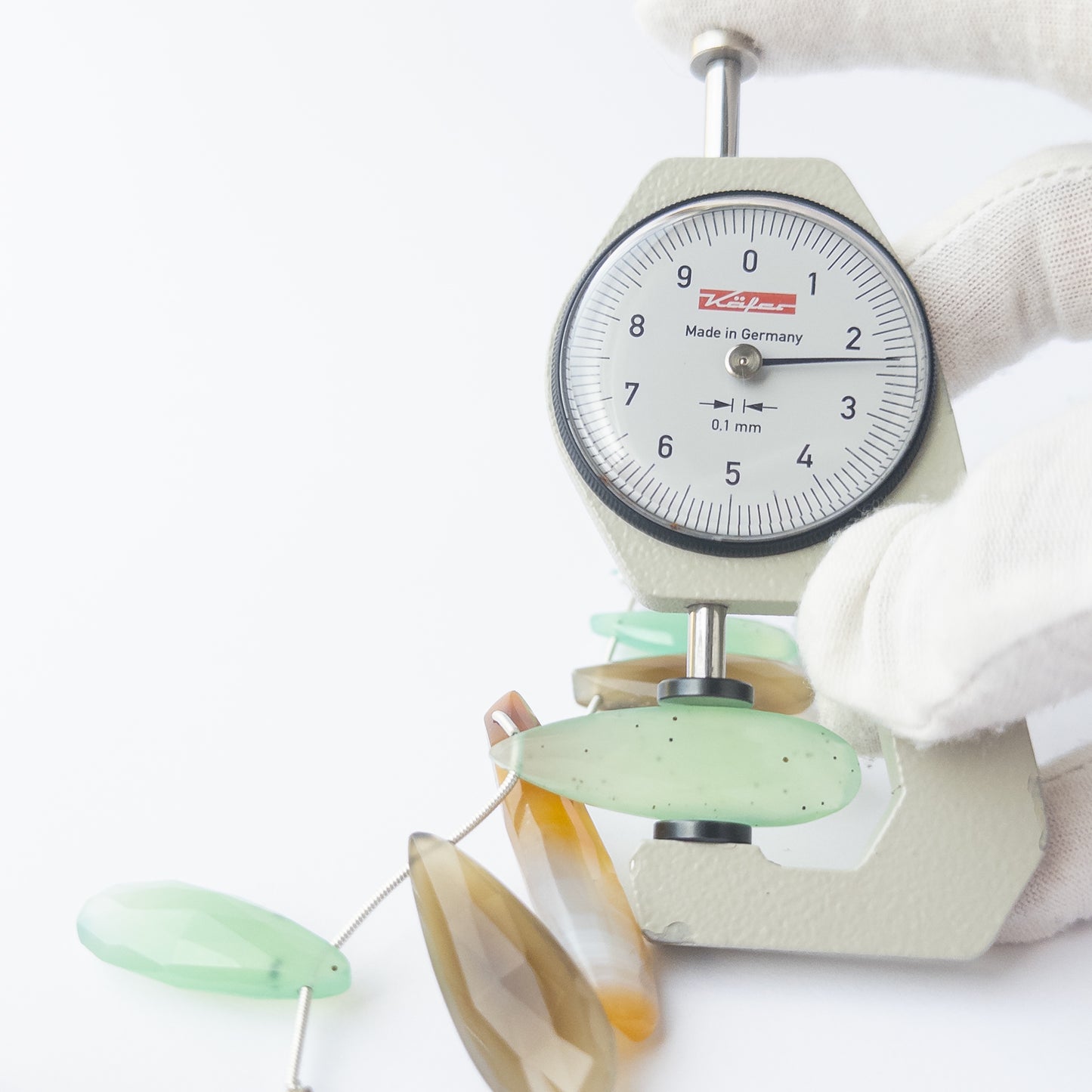 A dial gauge measures the Chalcedony faceted briolette 29–47mm gemstone.