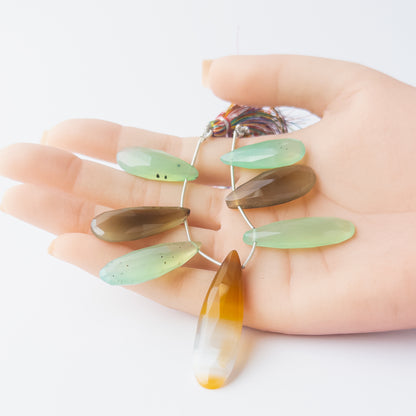 A person holds delicate strands of Chalcedony faceted briolette beads, highlighting their cut and size.