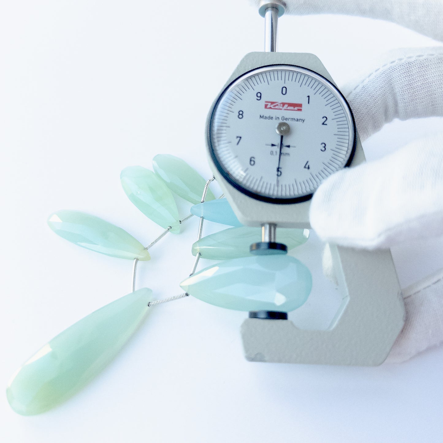A dial gauge measures the Chalcedony faceted briolette 29–45mm × 12–15mm gemstone.