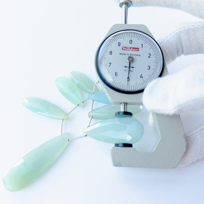 A dial gauge measures the Chalcedony faceted briolette 29–45mm × 12–15mm gemstone.