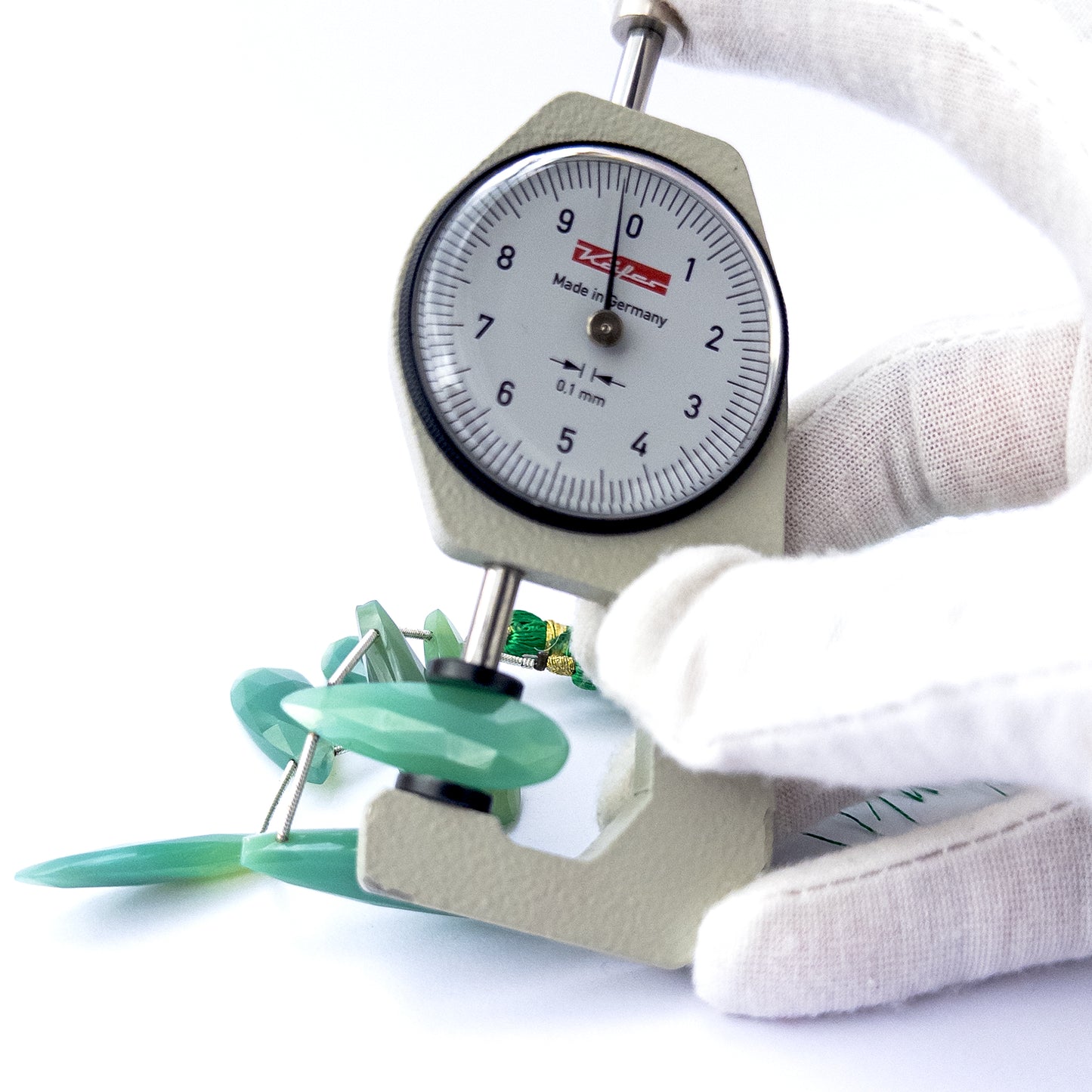 A dial gauge measures the Chalcedony faceted briolette 25–36mm gemstone.