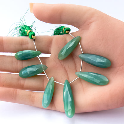 A person holds delicate pieces of Chalcedony beads, showcasing their faceted briolette design.
