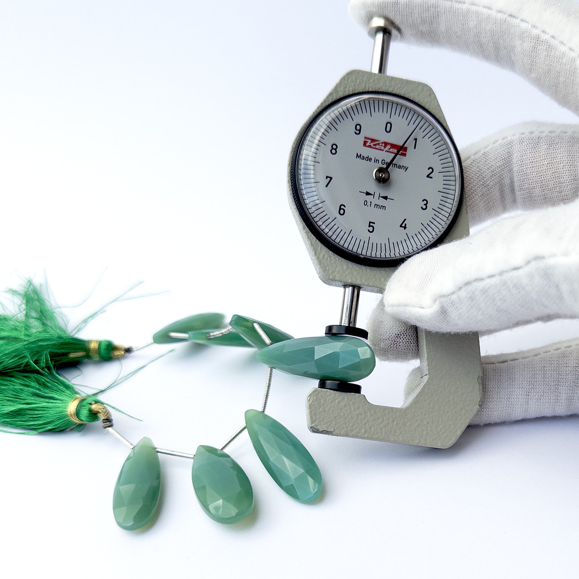 A dial gauge measures the Chalcedony faceted briolette 29–34mm gemstone.