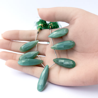 A person holds delicate strands of Chalcedony beads, showcasing their faceted briolette design.