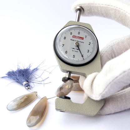 A dial gauge measures the Chalcedony faceted briolette 30–38mm gemstone.