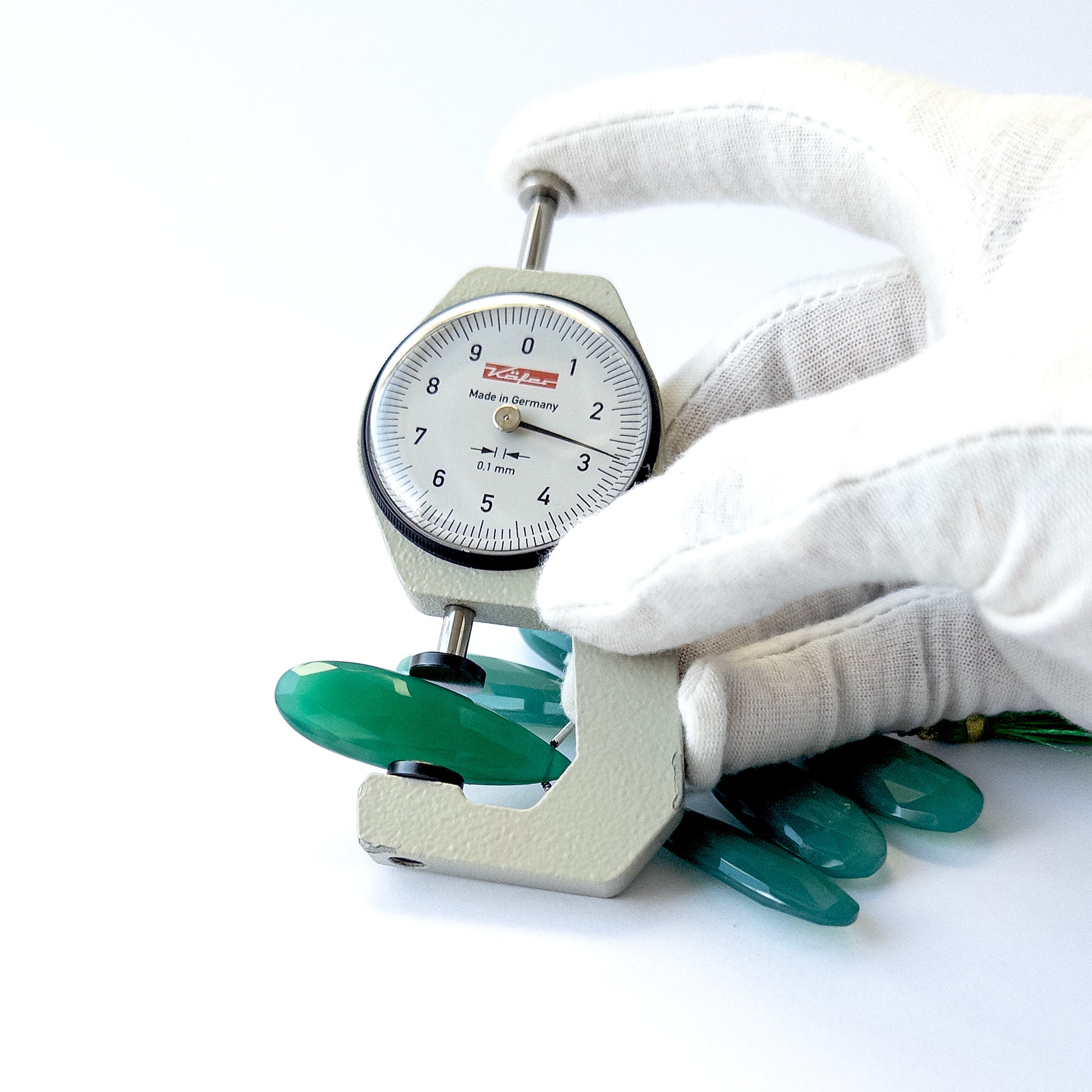 A dial gauge measures the Chalcedony faceted briolette 32–38mm gemstone.