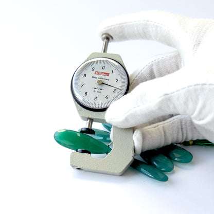 A dial gauge measures the Chalcedony faceted briolette 32–38mm gemstone.