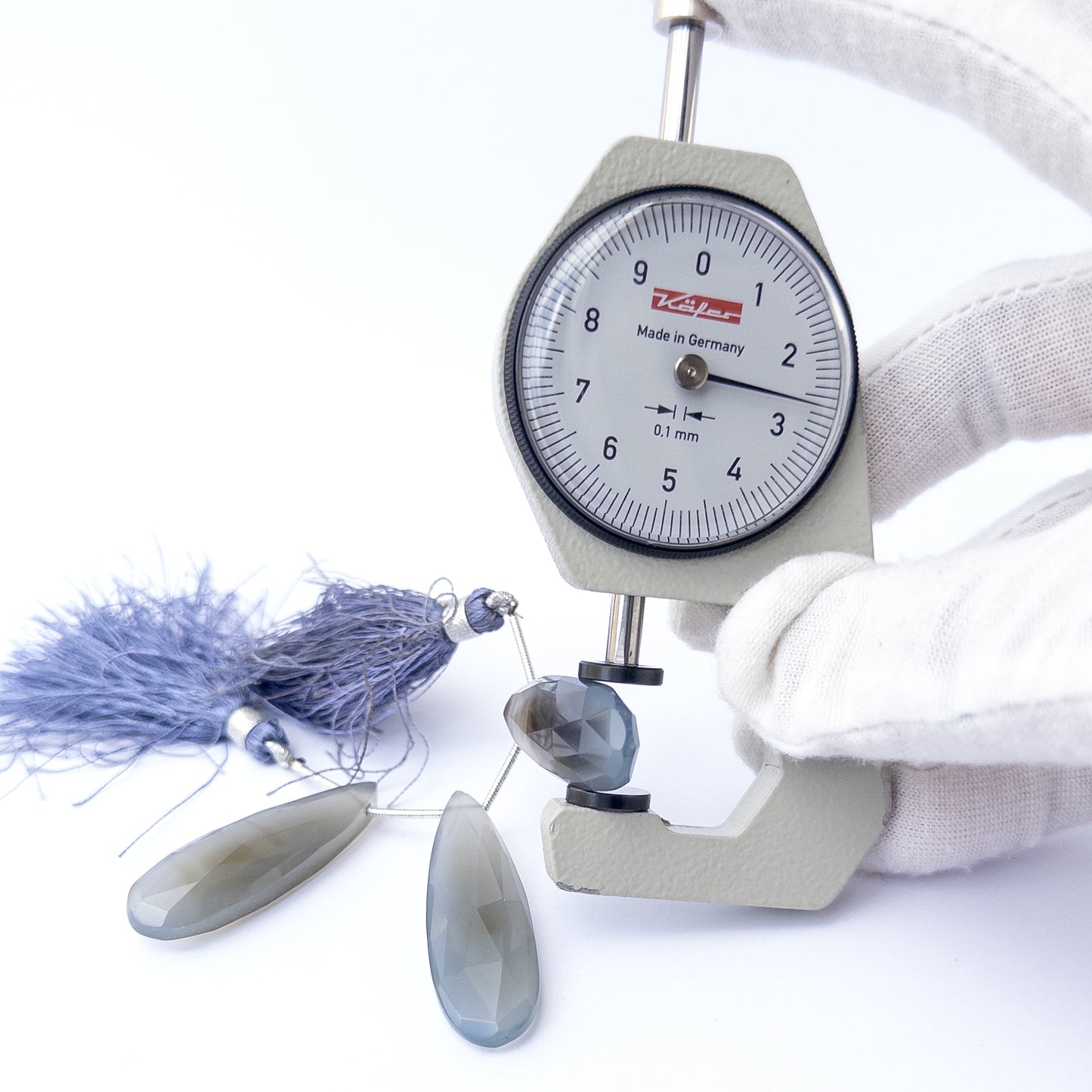 A dial gauge measures the Chalcedony faceted briolette 36–42mm gemstone.