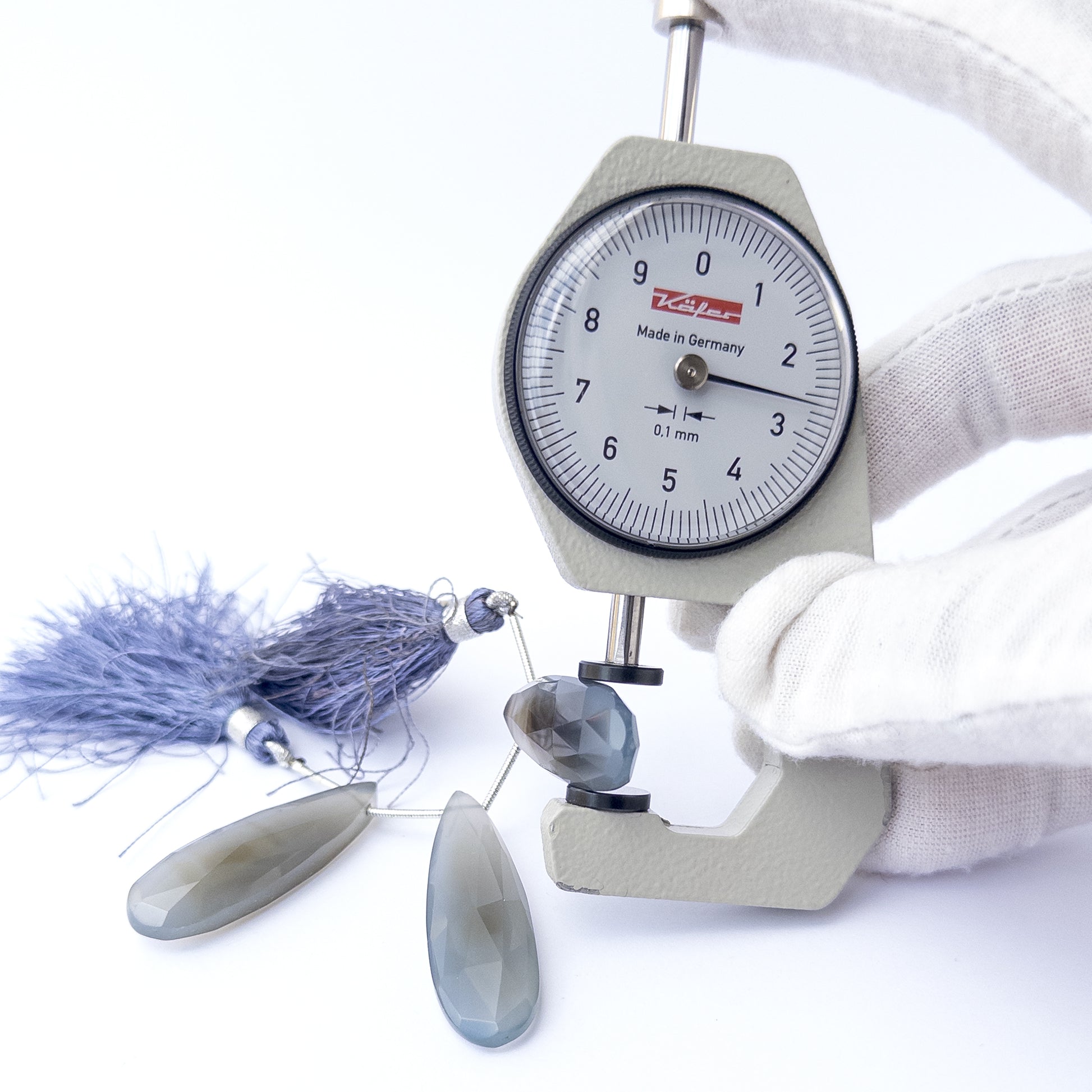 A dial gauge measures the Chalcedony faceted briolette 36–42mm gemstone.