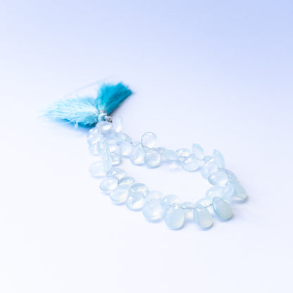 Genuine Chalcedony gemstone beads showcasing faceted briolette cuts arranged neatly on a 20cm strand.
