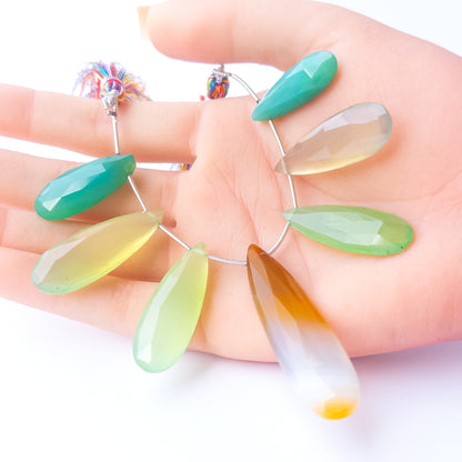A person holds delicate pieces of Chalcedony beads, showcasing their faceted briolette design.