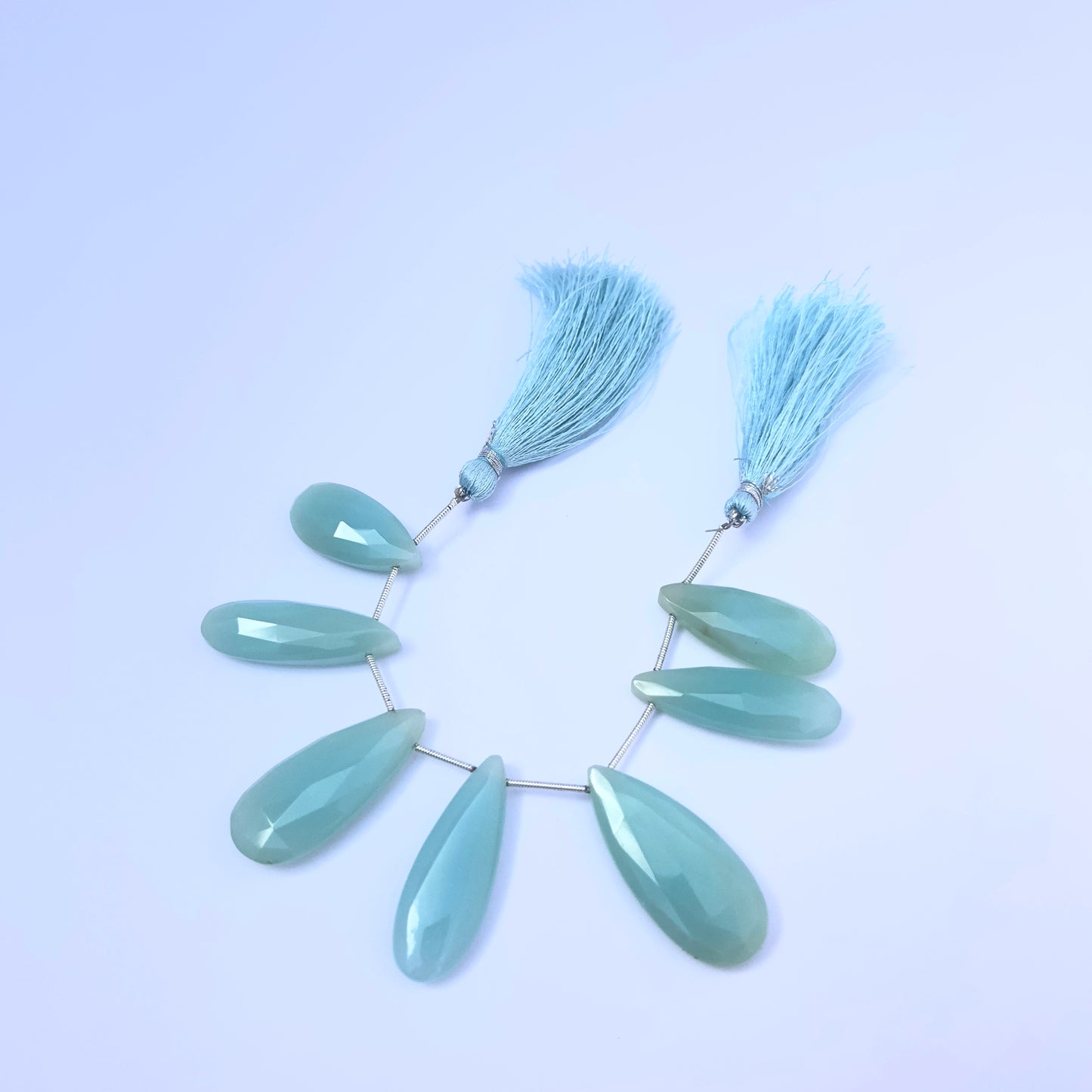 Stone beads in Chalcedony finish laid flat to highlight their 25×10.5mm to 35×15.4mm size and faceting.