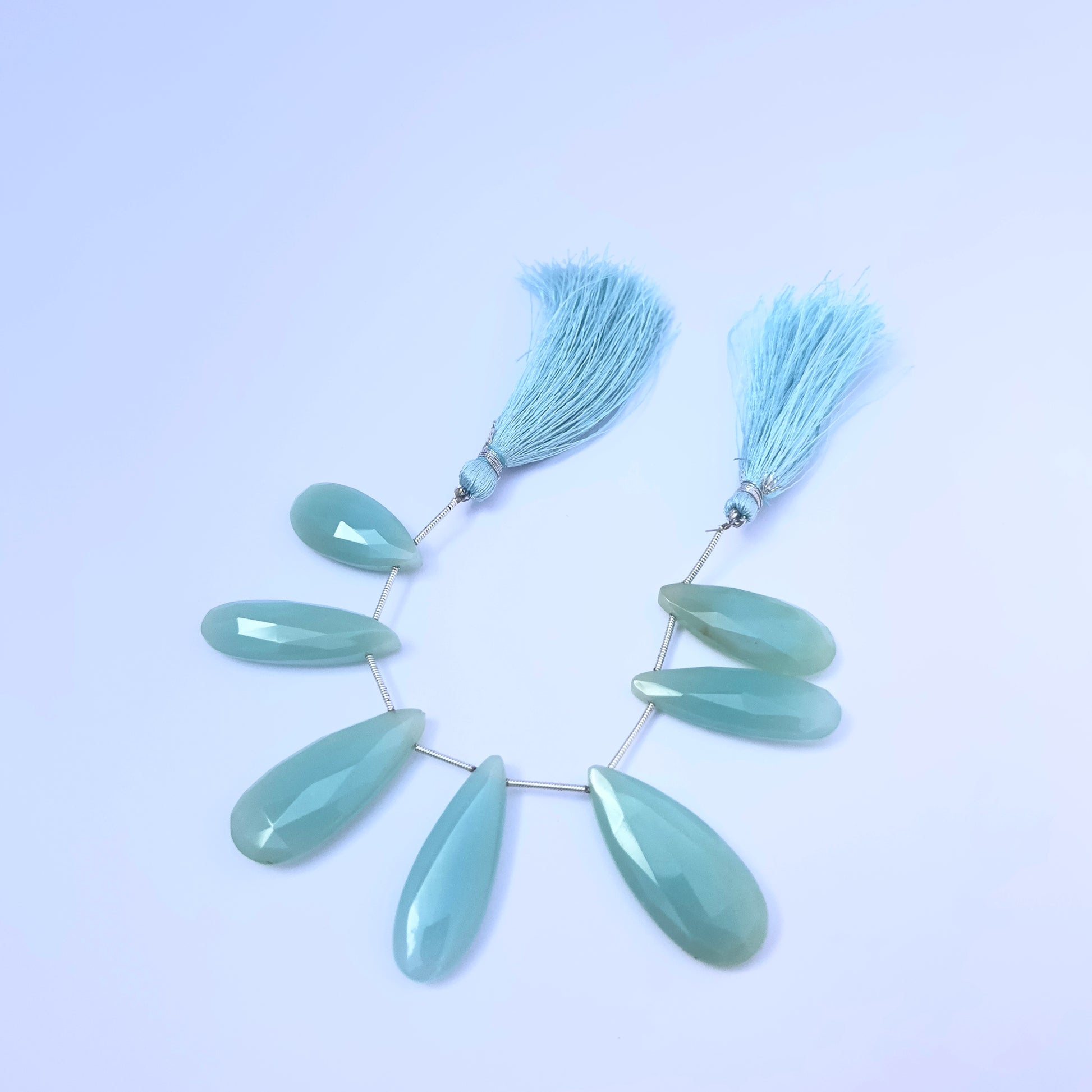 Stone beads in Chalcedony finish laid flat to highlight their 25×10.5mm to 35×15.4mm size and faceting.