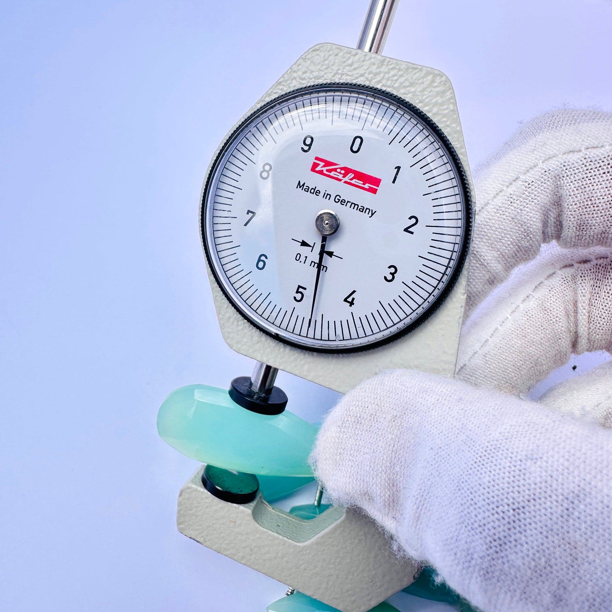 A dial gauge measures the Chalcedony faceted long pear briolette gemstone.