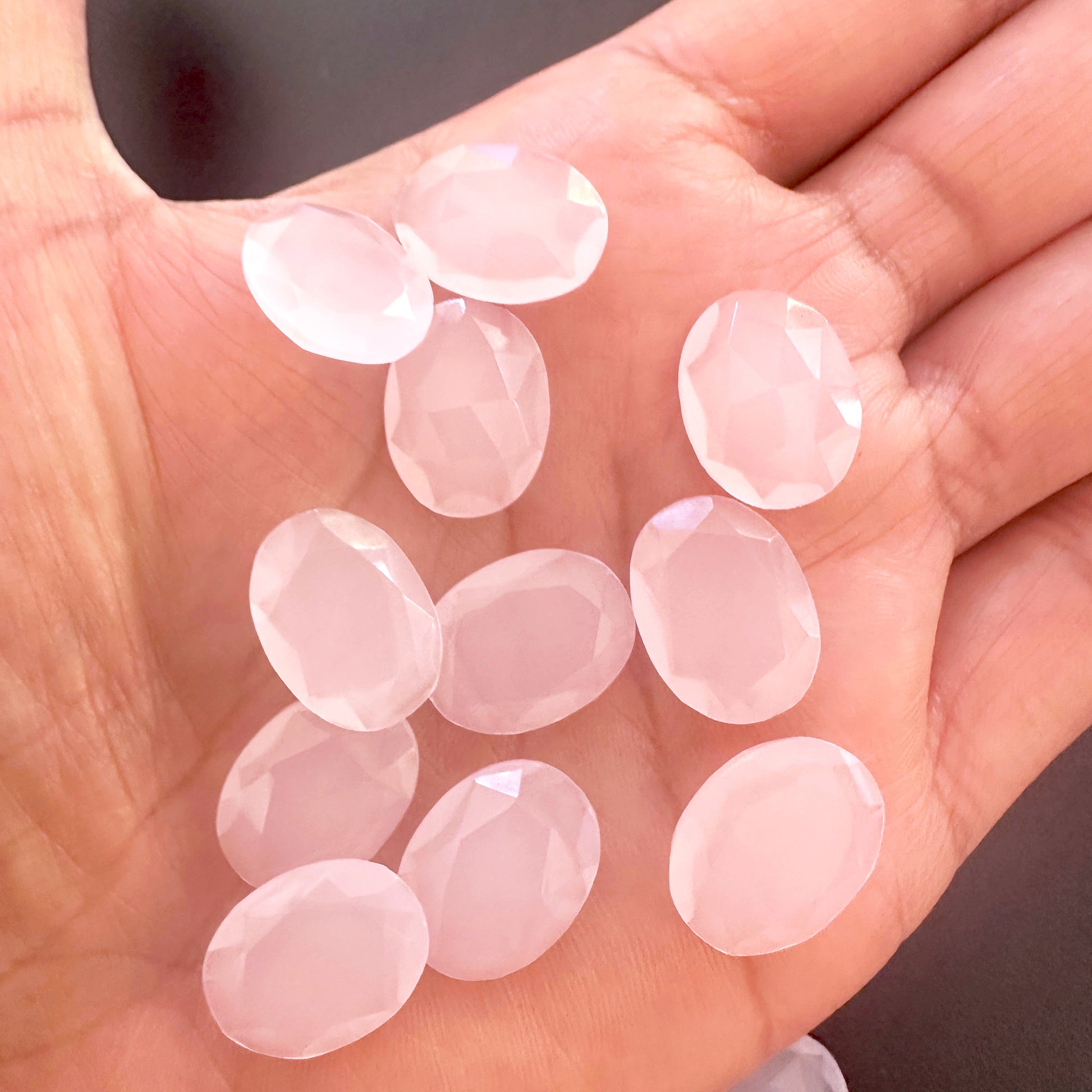 A person holds delicate strands of Chalcedony beads, showcasing their faceted design.