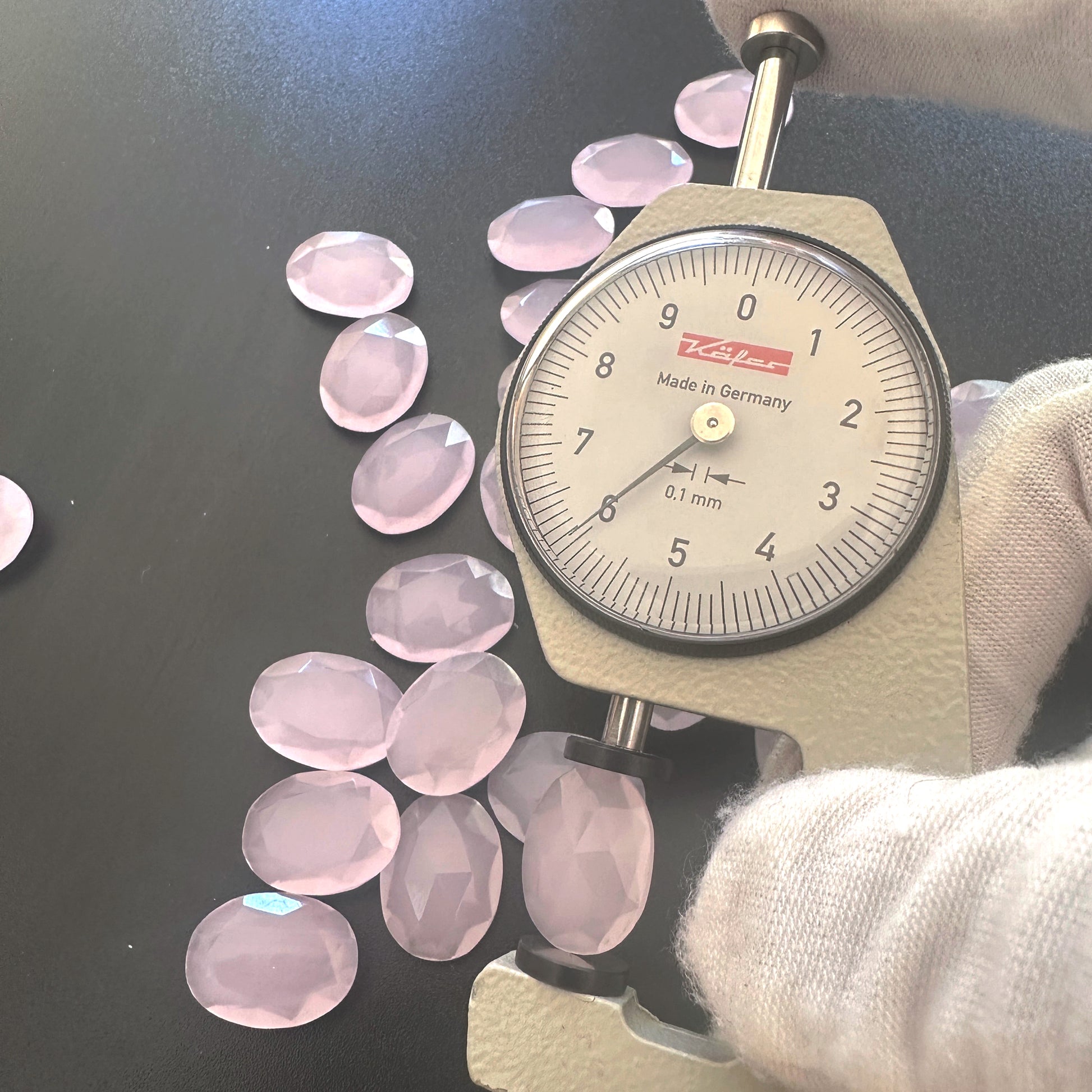 A dial gauge measures the Chalcedony faceted oval gemstone's breadth .