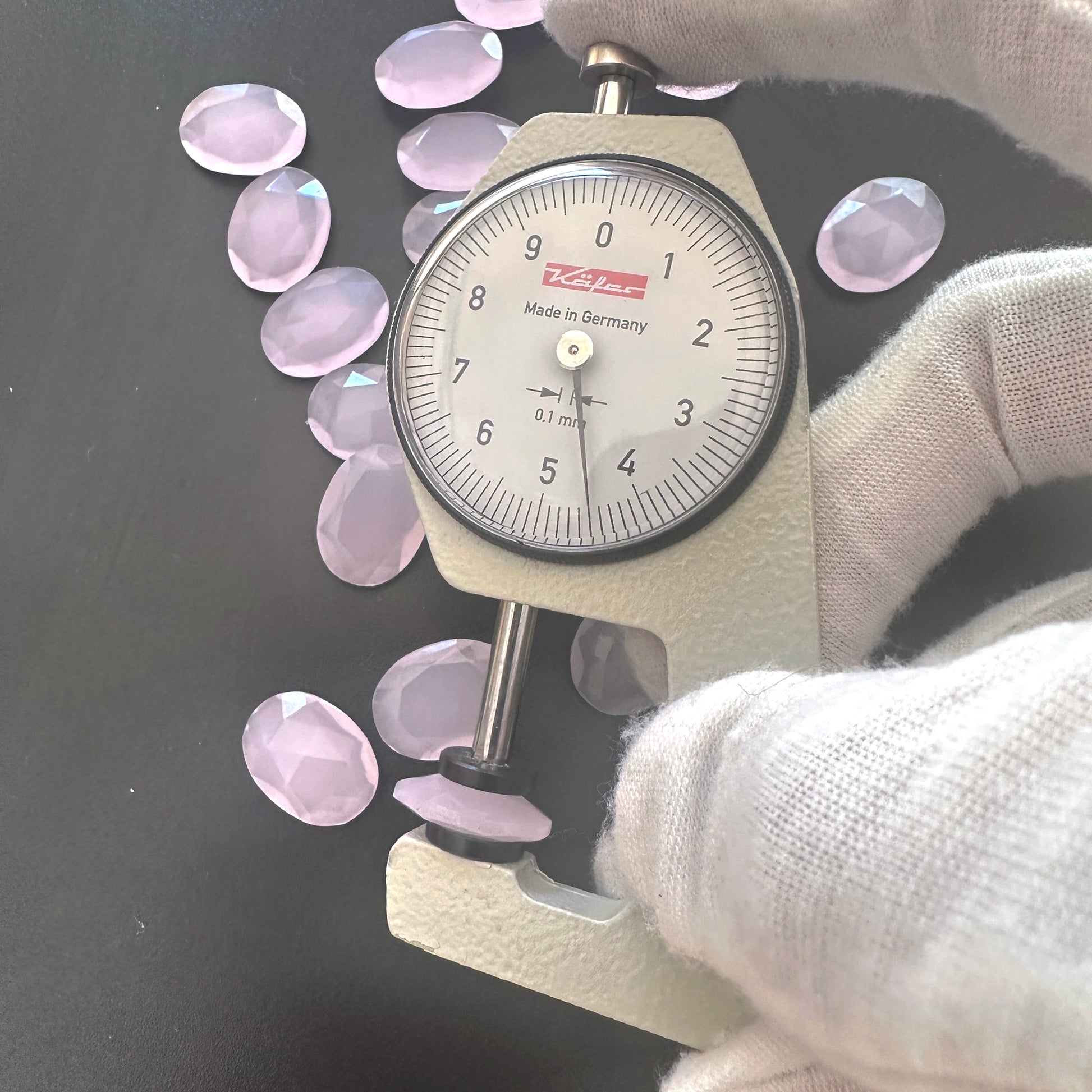 A dial gauge measures the Chalcedony faceted oval gemstone's thickness .