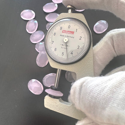 A dial gauge measures the Chalcedony faceted oval gemstone's thickness .