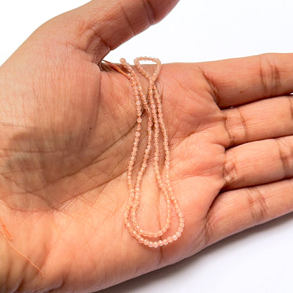 A person holds delicate strands of Chalcedony beads, showcasing their smooth design.
