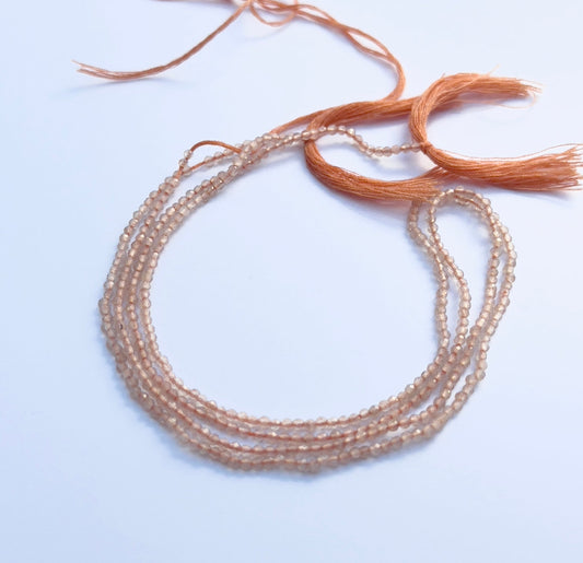 Natural chalcedony gemstone beads in faceted rondelle cut, 2mm size, arranged on a 32cm strand.