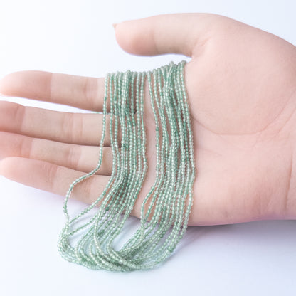 A person holds delicate strands of Chalcedony beads, showcasing their faceted rondelle design.