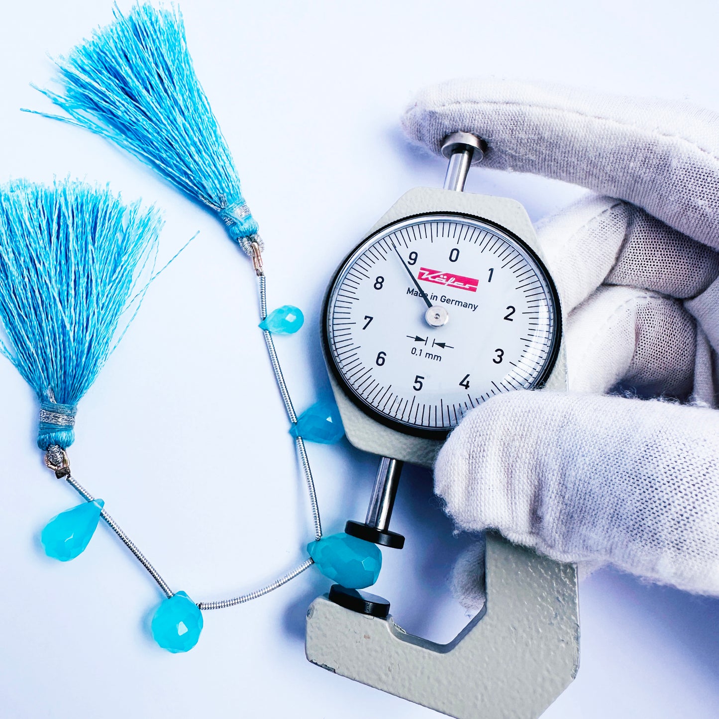 A dial gauge measures the Chalcedony faceted teardrop gemstone.