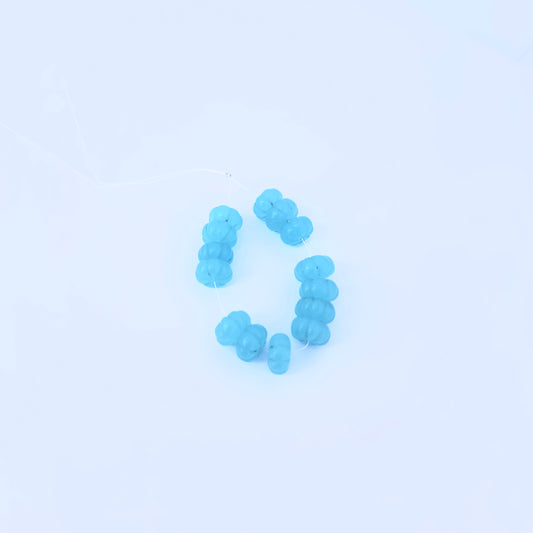 Chalcedony melon cut beads in translucent blue arranged on a white surface for jewellery making.