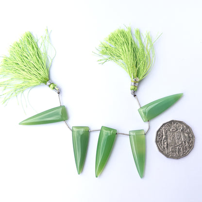 A coin is placed near delicate pieces of Chalcedony beads for scale.