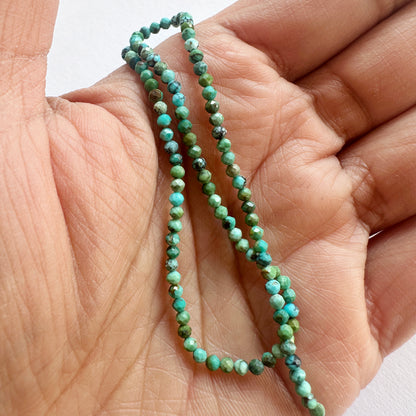 A person holds delicate strands of Chrysocolla beads, showcasing their smooth design.