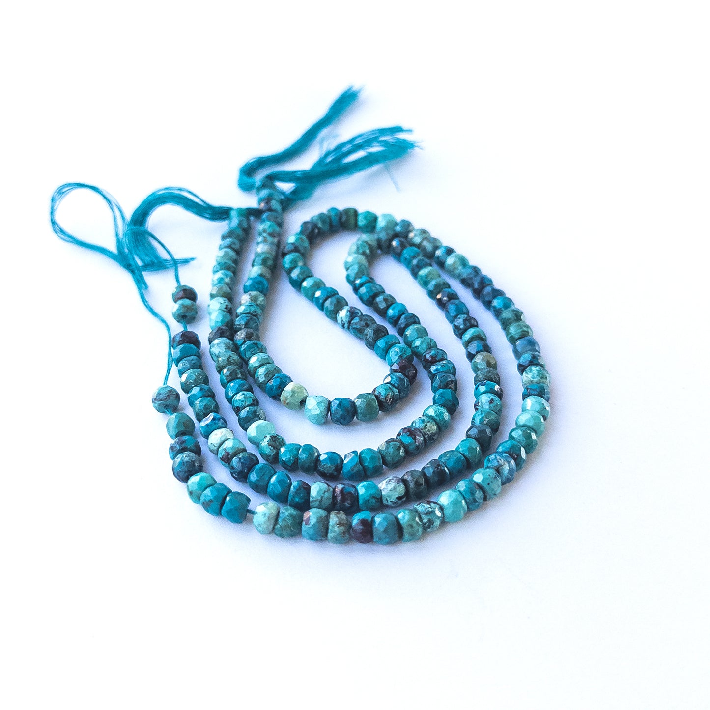 Premium Chrysocolla rondelle stone beads arranged neatly on a long strand with shimmering facets.