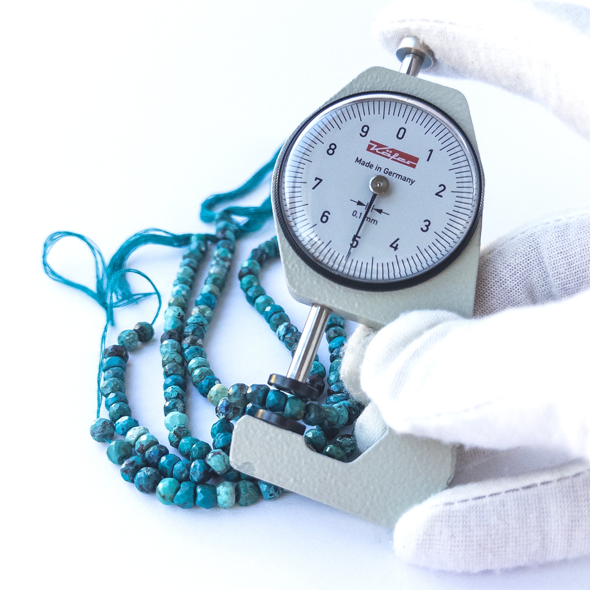 A dial gauge measures the Chrysocolla faceted rondelle 4–5mm gemstone.