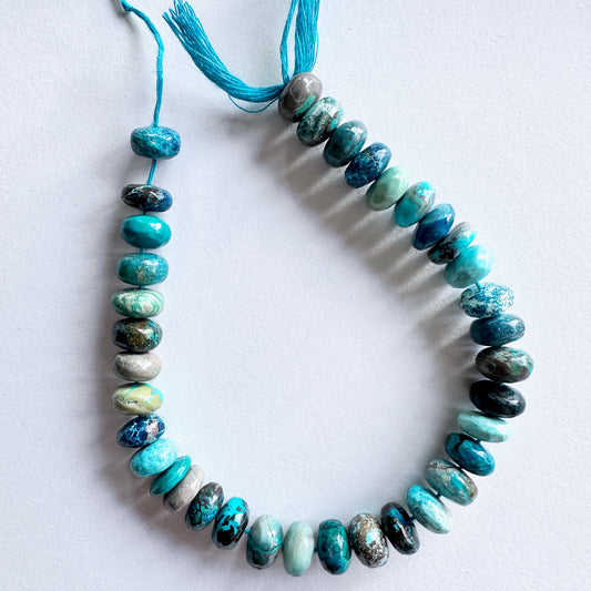 Smooth Chrysocolla rondelle beads in ocean blue tones with polished finish on a neatly arranged strand.