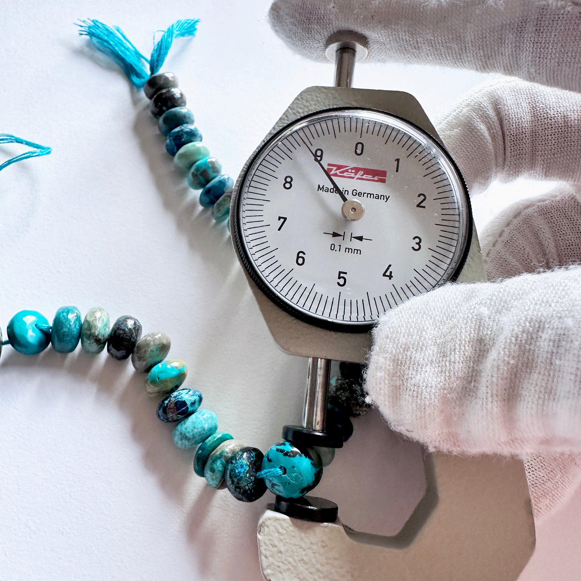 A dial gauge measures the Chrysocolla smooth rondelle 8-9mm gemstone.