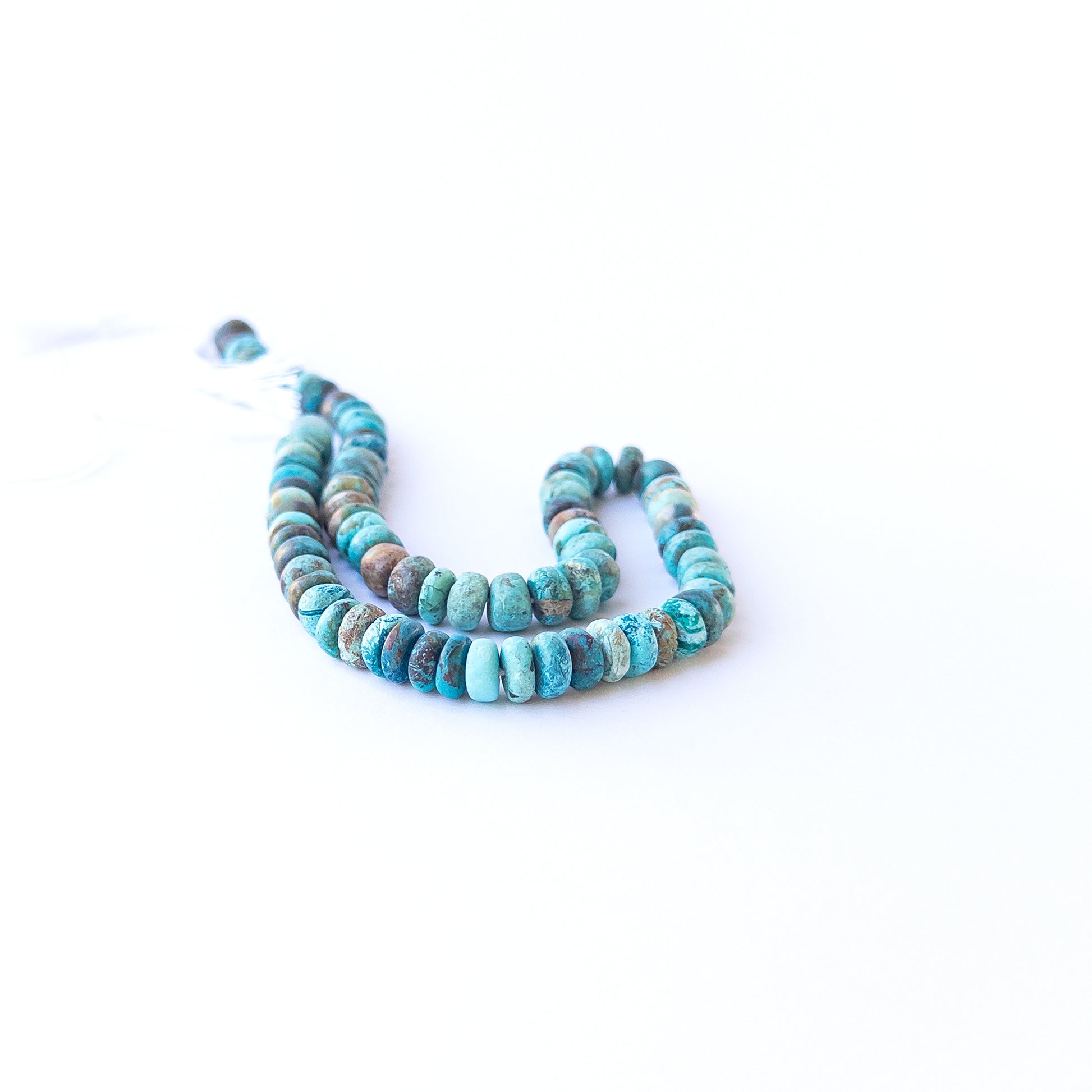 Chrysocolla smooth rondelle gemstone beads arranged in a vibrant blue‑green strand for DIY jewellery.