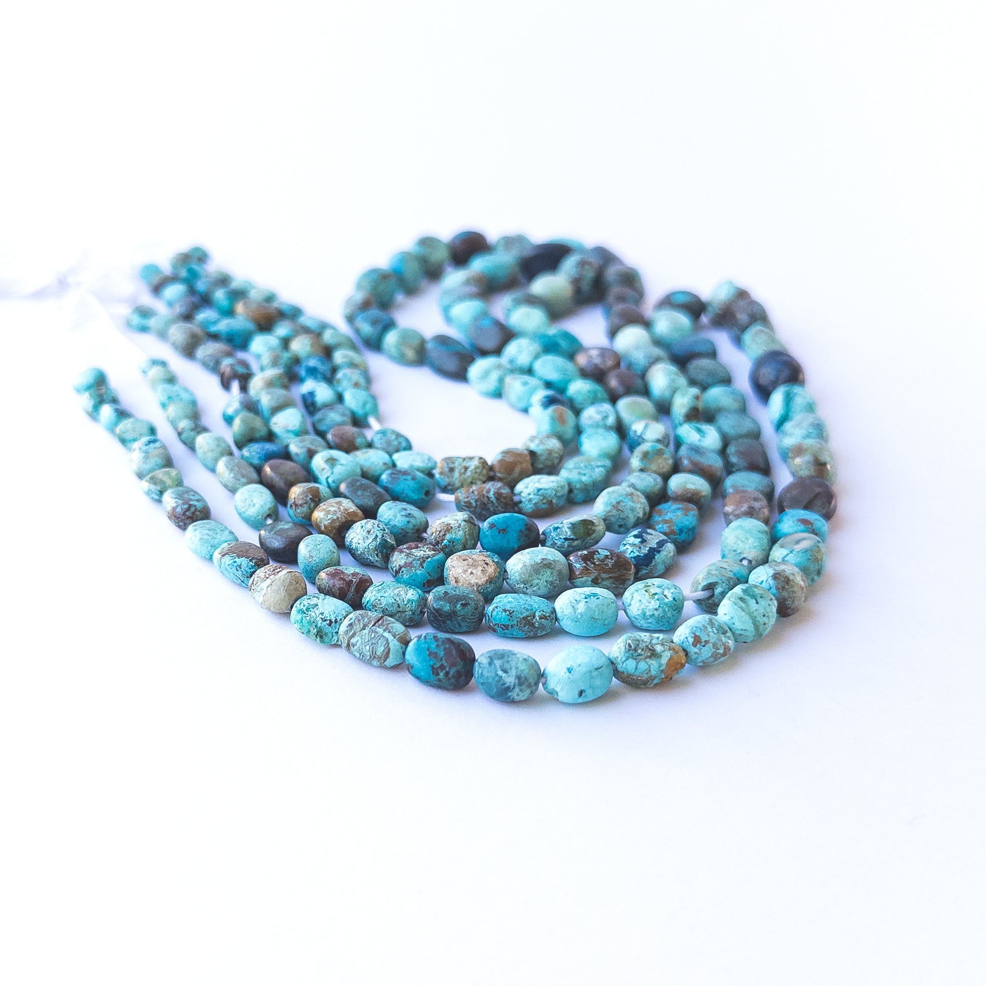 Close‑up of genuine Chrysocolla smooth tumble beads showing their rich colour mix and polished finish.