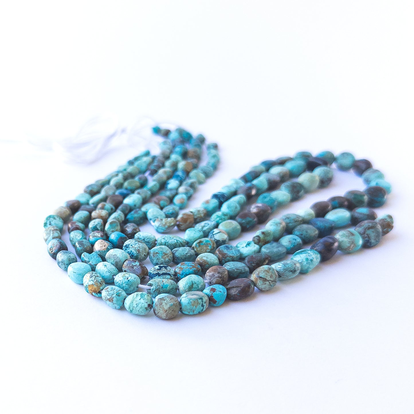 Chrysocolla smooth tumble beads displaying earthy blue‑green tones and natural texture.