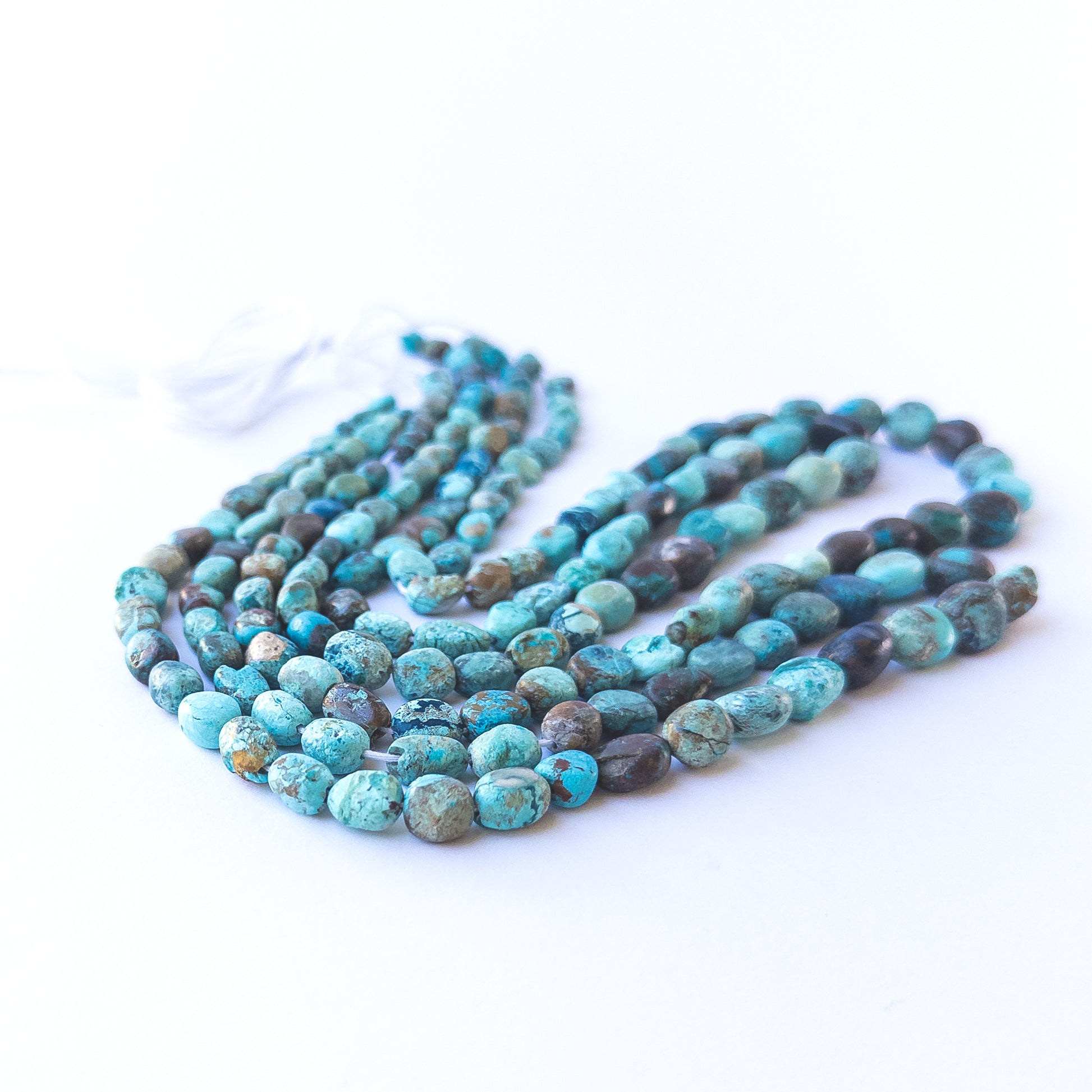 Chrysocolla smooth tumble beads displaying earthy blue‑green tones and natural texture.