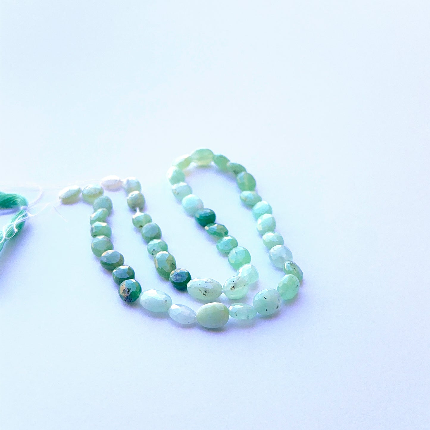 Vibrant green Chrysoprase faceted oval beads aligned on a strand highlighting clarity, cut quality and smooth finish.
