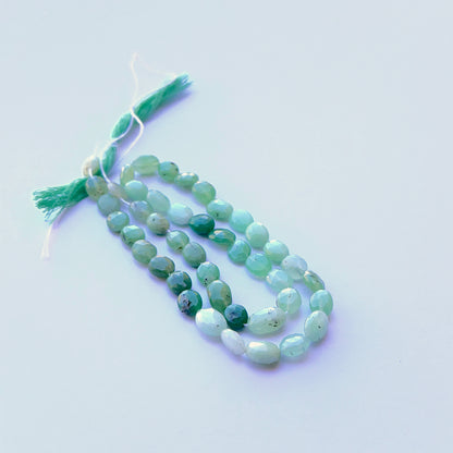 Chrysoprase faceted oval natural gemstone beads in bright green tones arranged on a 34cm strand for handmade jewellery components.
