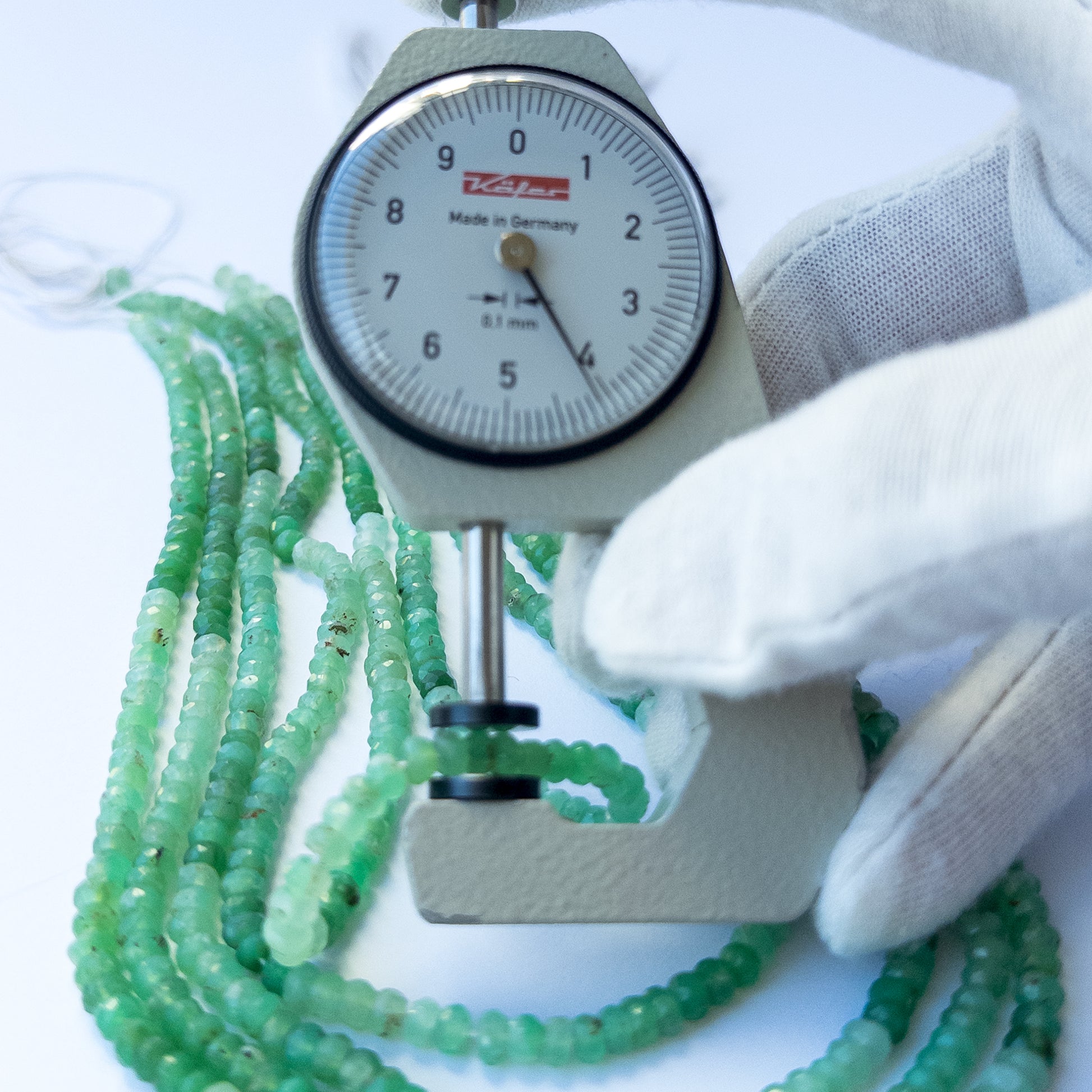 A dial gauge measures the Chrysoprase faceted rondelle 4.2–4.4mm gemstone.