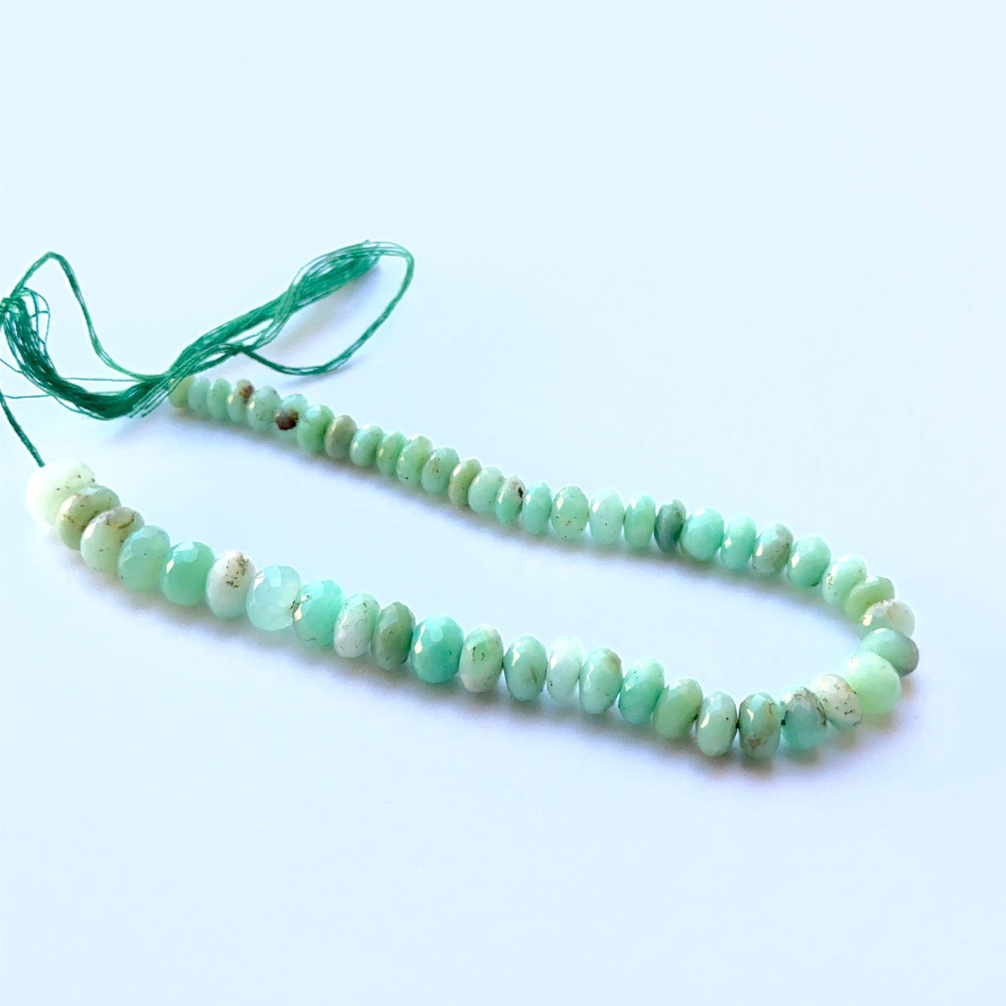 Chrysoprase faceted rondelle beads aligned on a strand highlighting clarity, shine and consistent shaping.