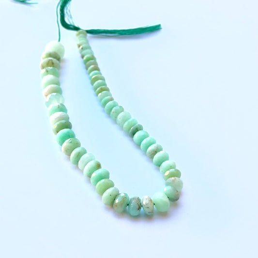Chrysoprase faceted rondelle natural gemstone beads in bright green tones arranged on a 19cm strand for handmade jewellery components.