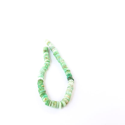 Chrysoprase smooth wheel beads in fresh green tones arranged on a strand for handmade jewellery components.