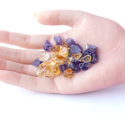 A person holds delicate pieces of Citrine and Amethyst rough, showcasing their natural design.