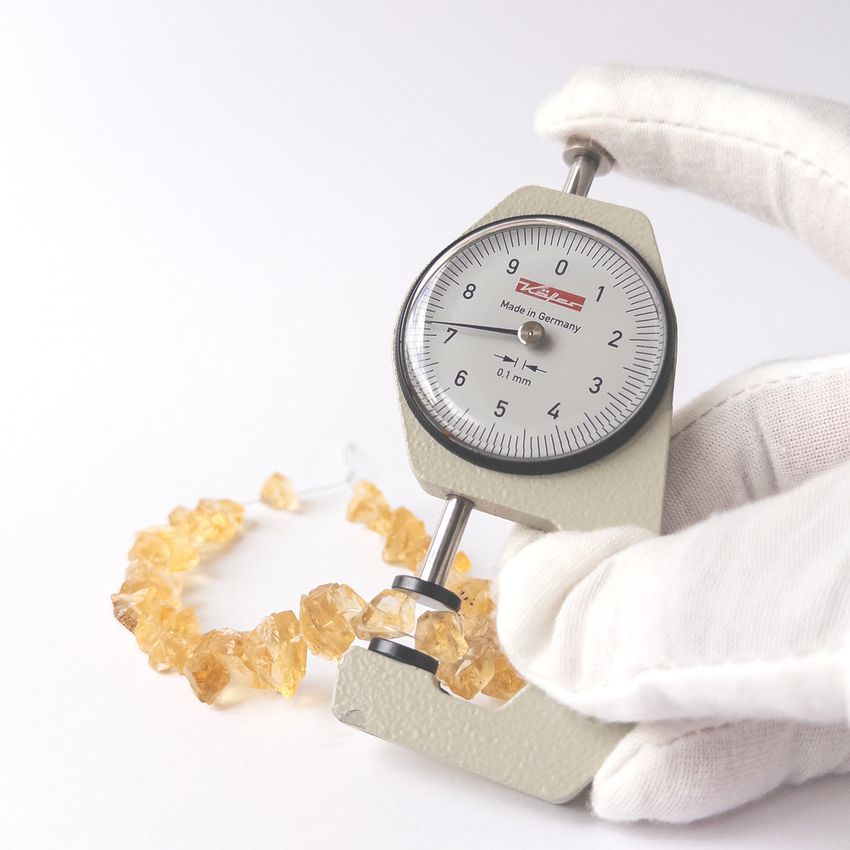 A dial gauge measures the Citrine drilled rough 6.5–7.5mm gemstone.