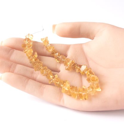 A person holds delicate pieces of Citrine rough beads, showcasing their drilled rough design.