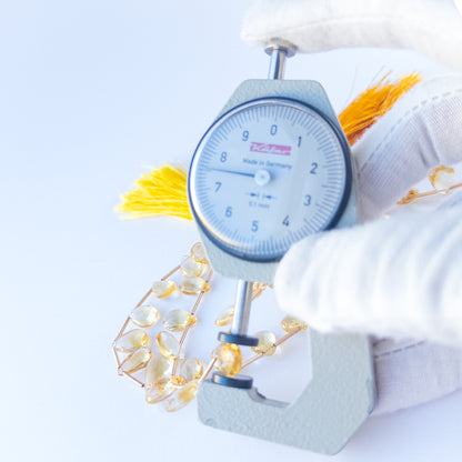 A dial gauge measures the Citrine faceted briolette 7–7.5mm gemstone.